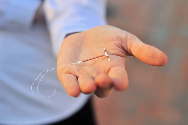 Holding an IUD birth control device in hand Holding an IUD birth control copper coil device in hand, used for contraception iud stock pictures, royalty-free photos & images