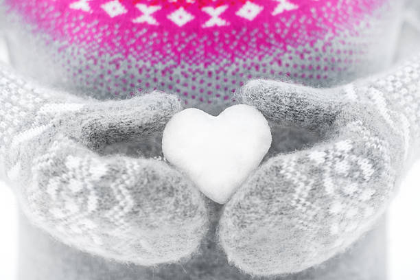 Holding heart-shaped snowball stock photo
