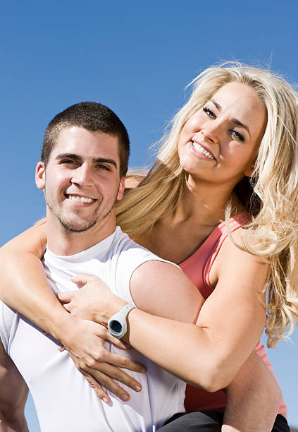 Holding on Young woman holding on to her boyfriend as he gives her a piggy back.Utah  2 teenage boys men blond hair muscular build stock pictures, royalty-free photos & images