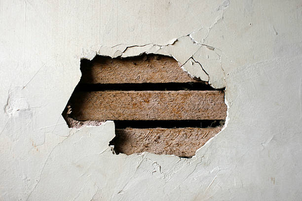 hole in plaster wall - exposed wood paneling - gat stockfoto's en -beelden