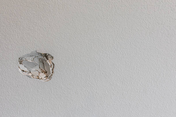 A hole in the wall of a hallways caused by a fist punching through the wall stock photo