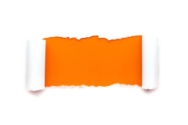 A hole in white paper with torn edges isolated on a white background with a bright orange color paper background inside. stock photo