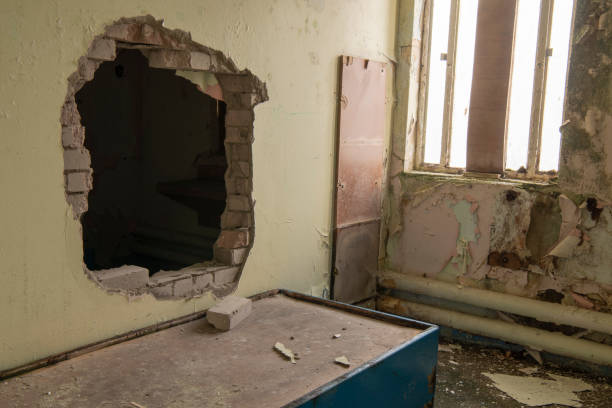 Hole punched through the wall between two prison cells Hole punched through the wall between two prison cells strangford lough stock pictures, royalty-free photos & images