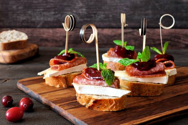 Holiday crostini skewers with cranberry sauce Holiday crostini skewers with cranberry sauce, brie, salami, and mint on a wooden server appetizer stock pictures, royalty-free photos & images