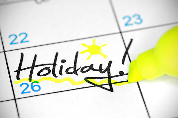 Holiday date in calendar Close-up of underlined in yellow "Holiday" date handwriting word in a white calendar, with exclamation mark and a little sun hand drawn. holiday calendars stock pictures, royalty-free photos & images