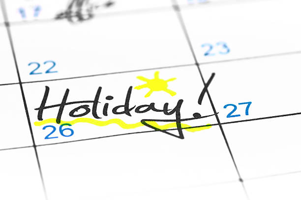 Holiday date in calendar Close-up of underlined in yellow "Holiday" date handwriting word in a white calendar, with exclamation mark and a little sun hand drawn. holiday calendars stock pictures, royalty-free photos & images