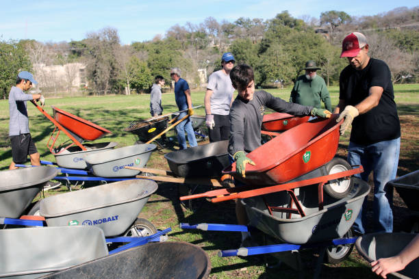 MLK Holiday Day of Service, Pease Park, Austin, Texas Austin, Tx, USA - Jan. 21, 2019:  An adult and teenager team of  volunteers collect wheelbarrows in Pease Park near the end of the Martin Luther King Holiday Day of Service. martin luther king jr day stock pictures, royalty-free photos & images