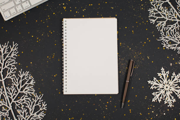 Holiday white decorations and notebook on black background. stock photo