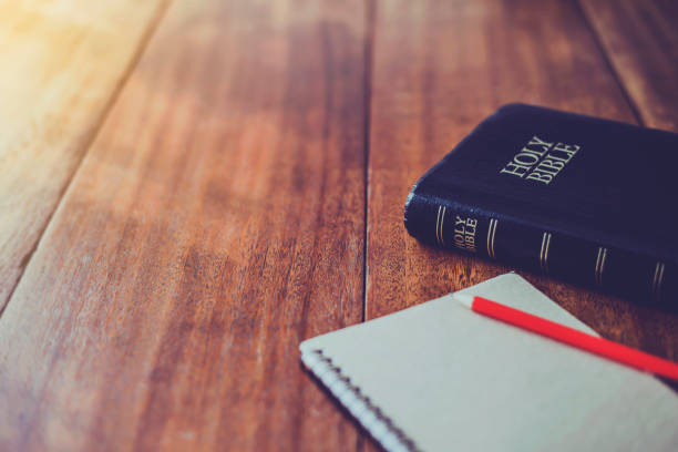Holy bible with note book and pencil on wooden table against morning  sun light for christian devotion, copy space stock photo