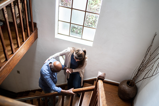 Home caregiver helping senior man walking up the stairs at home