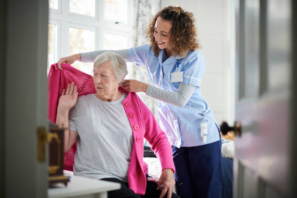 home carer visit home carer helping senior woman get dressed in her bedroom home caregiver stock pictures, royalty-free photos & images