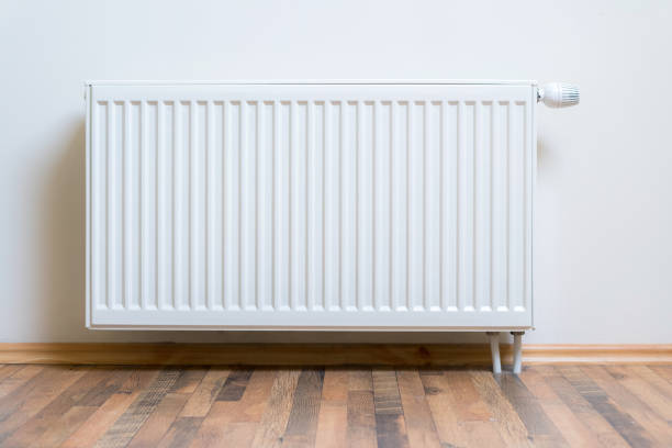 riscaldatore del radiatore domestico sulla parete bianca sul pavimento in legno. attrezzatura di riscaldamento regolabile per appartamento e casa - riscaldamento foto e immagini stock