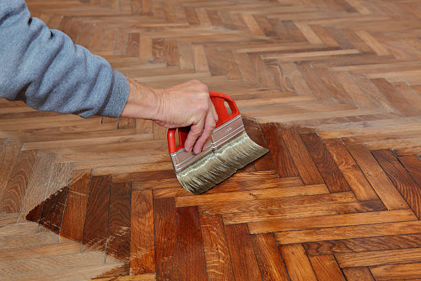 Home renovation Varnishing of oak parquet floor, workers hand and brush parquet floor stock pictures, royalty-free photos & images