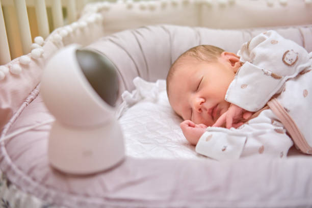 A home surveillance camera looks at the crib with a sleeping newborn baby  baby monitor stock pictures, royalty-free photos & images
