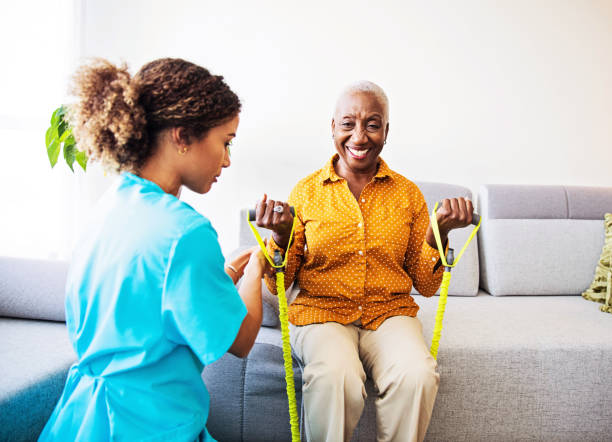 Home Visit - Nurse and her  Patient Nurse home visiting a patient, showing her exercises for arms strenght physical therapy stock pictures, royalty-free photos & images