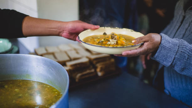 Homeless Help Passing of a plate with stew soup and bread kitchen food handouts to the homeless and poor during Lockdown south africa covid stock pictures, royalty-free photos & images