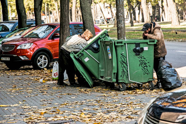 Homeless people are looking for food in a dumpster. Selective focus, street photo, urban poverty. stock photo
