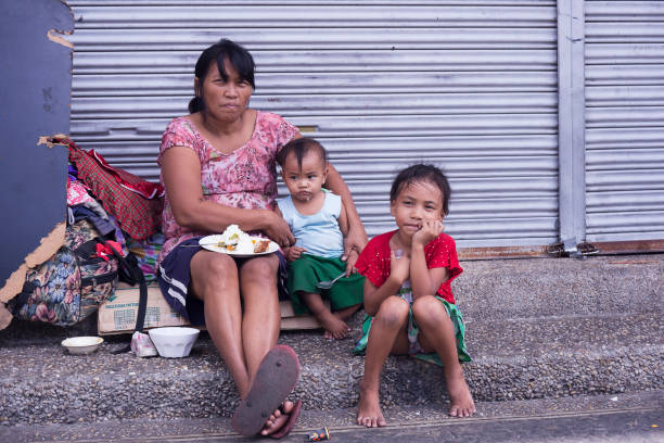 Homeless woman with her children Manila, Philippines - December 21, 2016: Homeless filipino woman with two little children in the streets of Manila philippines girl stock pictures, royalty-free photos & images