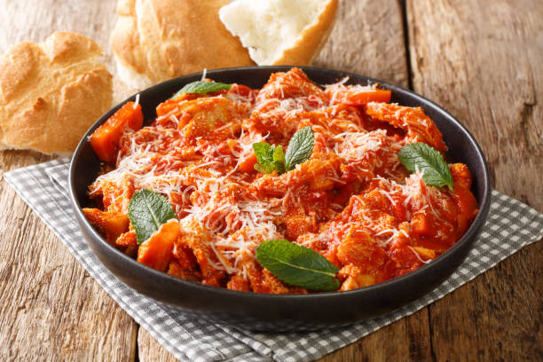 Homemade braised tripe in tomato sauce with cheese and herbs close-up in a plate. horizontal stock photo
