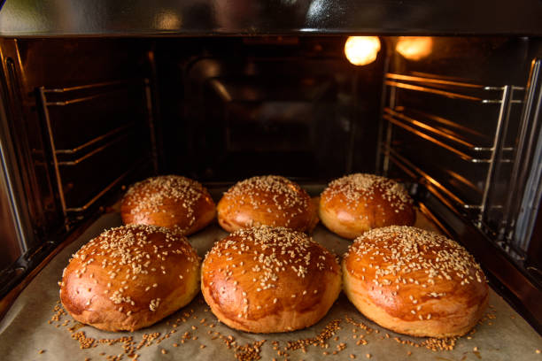 homemade burger rolls sprinkled with sesame seeds are baked in the oven stock photo