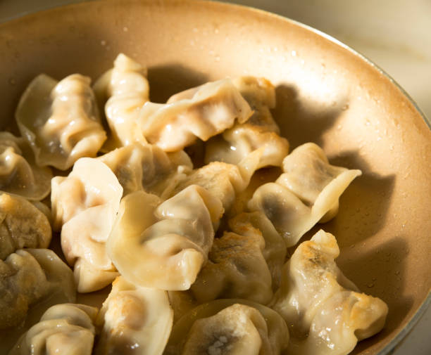 Homemade Chinese fried dumpling in frying pan is cooking stock photo