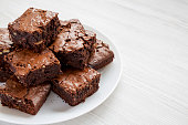 istock Homemade chocolate brownies on a white plate on a white wooden background, side view. Copy space. 1167515863