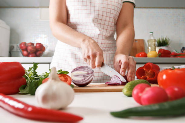 homemade cooking. woman in the kitchen cutting red onions on a c - woman chopping vegetables imagens e fotografias de stock