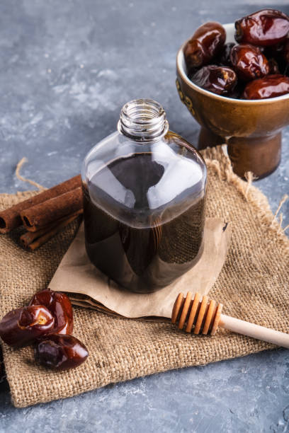 Homemade dates syrup in glass bottle on gray stone table. Alternative food and drink Trend food 2020. Copy space. stock photo