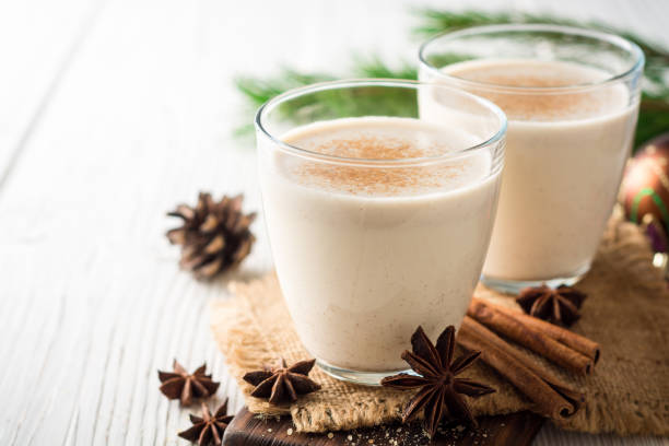 Homemade eggnog with grated nutmeg and cinnamon on white wooden table. Traditional Christmas drink. stock photo