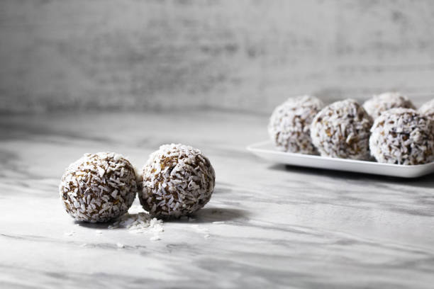 Homemade energy balls with dried apricots, raisins, dates, prunes, walnuts and coconut. Healthy sweet food. Energy balls in a plate on a marble gray background. Close up. Side view. Copy space  plasma ball stock pictures, royalty-free photos & images