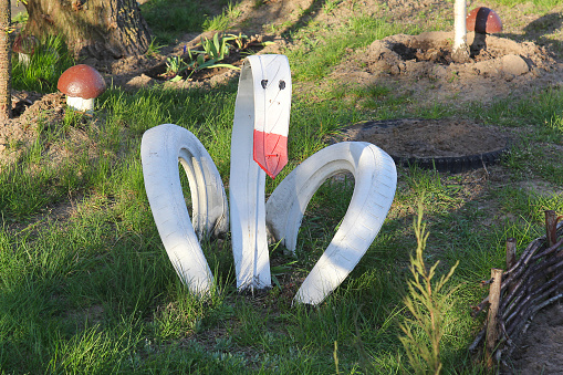 Homemade garden sculpture - a swan made of old car tire.  Waste upcycling concept. Accomplishment of yard.