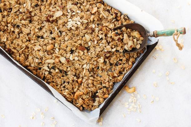 Homemade Granola in a parchment lined baking sheet, selective focus stock photo