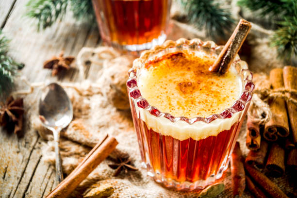 Homemade Hot Buttered Rum Winter holidays traditional drink, homemade hot buttered rum with spices, over old rustic wooden background with christmas tree branches, copy space rum stock pictures, royalty-free photos & images