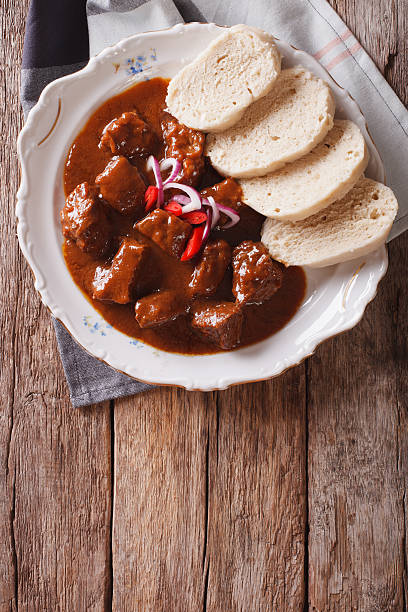 homemade hot Czech goulash with knodel close-up. vertical top view homemade hot Czech goulash with knodel in a plate close-up. vertical top view czech culture stock pictures, royalty-free photos & images