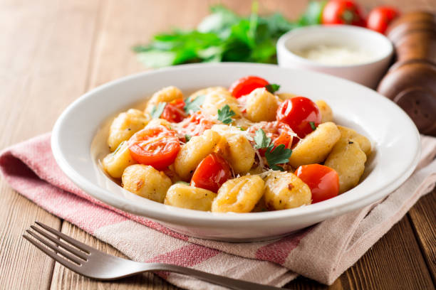 Homemade italian gnocchi with tomato, garlic, parsley and parmesan cheese on wooden table. stock photo
