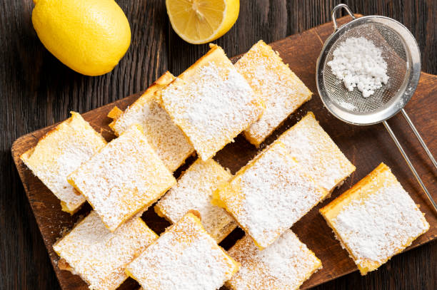 Homemade lemon bars with shortbread crust, on wooden background. stock photo