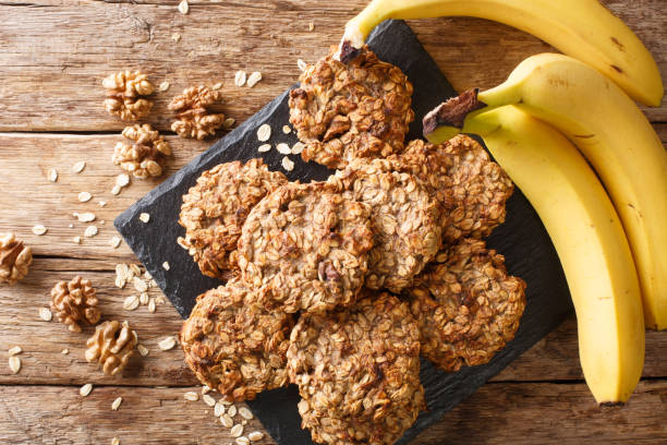 Homemade low-calorie banana cookies with oatmeal and walnuts close-up on a slate board. Horizontal top view Homemade low-calorie banana cookies with oatmeal and walnuts close-up on a slate board on the table. Horizontal top view from above cookie stock pictures, royalty-free photos & images