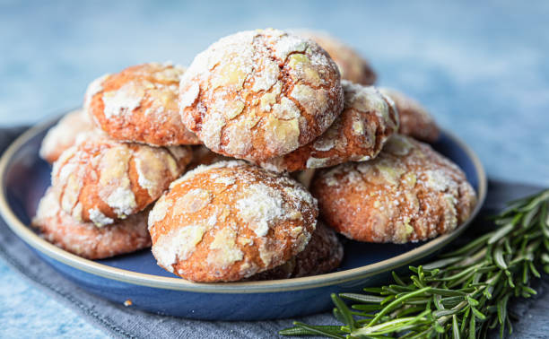 Homemade orange shortbread crinkle cookies with powdered sugar, rosemary and Sicilian blood oranges on blue concrete background. stock photo