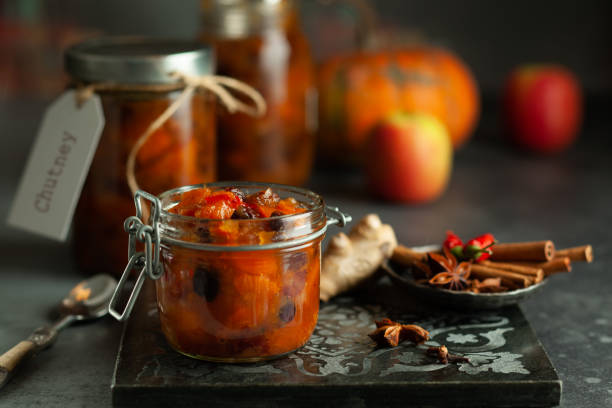 Homemade pumpkin and apple chutney Homemade pumpkin and apple chutney with raisins in jars on a table. Delicious sweet spicy sauce preserved for autumn and winter season. chutney stock pictures, royalty-free photos & images