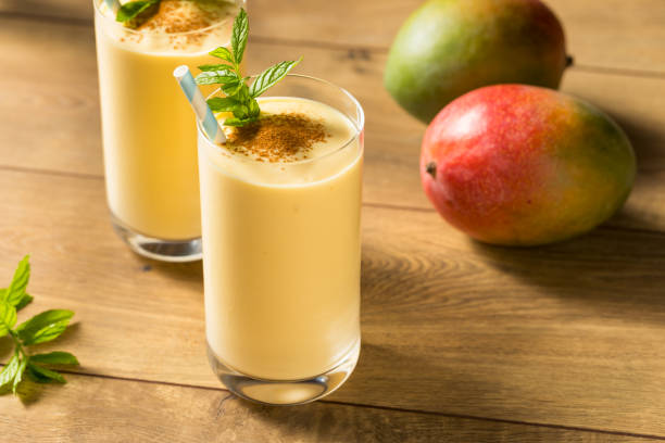 Homemade Sweet Indian Mango Lassi Homemade Sweet Indian Mango Lassi Smoothie with Mint mango smoothie stock pictures, royalty-free photos & images