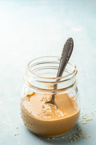 Homemade Tahini sauce in glass jar on concrete background stock photo