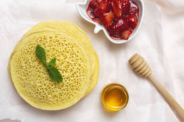 Homemade traditional moroccan baghrir with honey, strawberries and mint from above stock photo