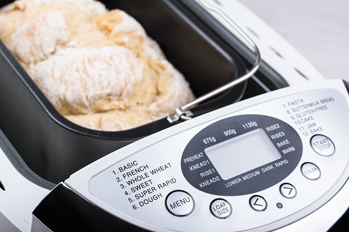 Homemade white flour bread baked in bread maker with digital display.