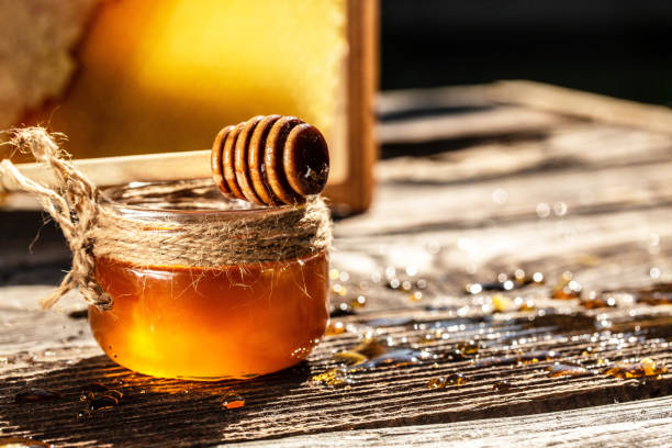 Honey dripping from a wooden honey dipper in a jar on wooden rustic background. honeycombs with full cells of honey. banner, menu, recipe, place for text Honey dripping from a wooden honey dipper in a jar on wooden rustic background. honeycombs with full cells of honey. banner, menu, recipe, place for text, honey photos stock pictures, royalty-free photos & images