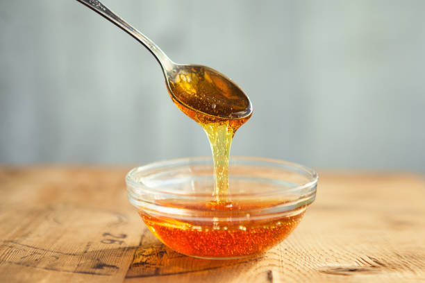 honing die van lepel in de kop druipt - honing stockfoto's en -beelden