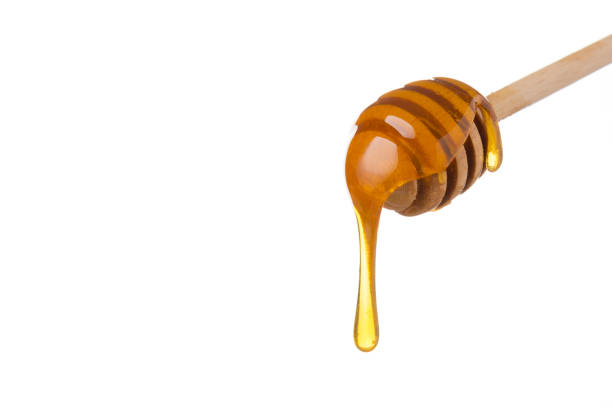 Honey dripping from wooden honey spoon stock photo