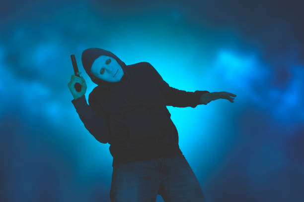 Hooded man with a gun falling down stock photo