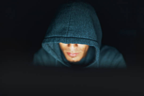 hoodie-dragen jongeman ziet er sinistere, werken op computer bij nacht - student night study stressed stockfoto's en -beelden