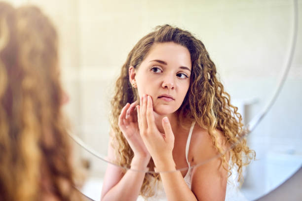 I hope a pimple isn't popping up here Shot of a young woman squeezing a pimple on her face in the bathroom at home imperfection stock pictures, royalty-free photos & images