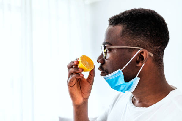 I hope this isn't a sign of the virus One African man Trying to Sense Smell of a Lemon at home during the day, smell blindness is one of the possible symptoms of covid-19. scented stock pictures, royalty-free photos & images